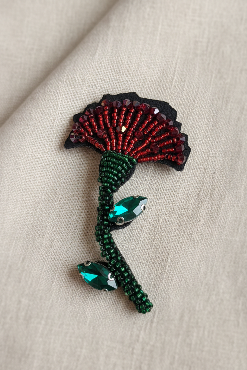 Broche flor bordada vermelha com haste verde sobre tecido elegante