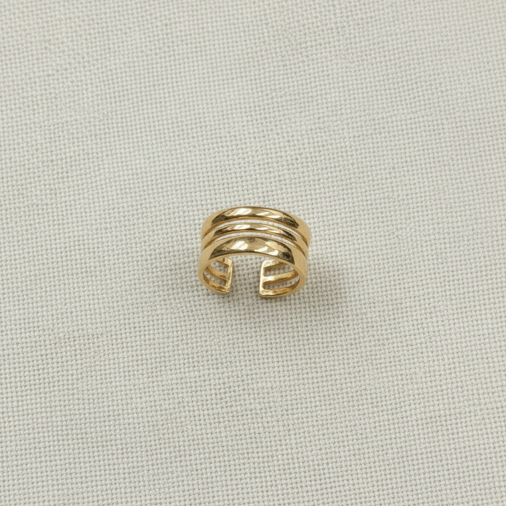 Ear cuff deitado sobre linho — flat lay