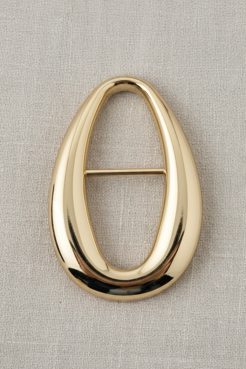Passante oval gota dourado sobre fundo de tecido linho