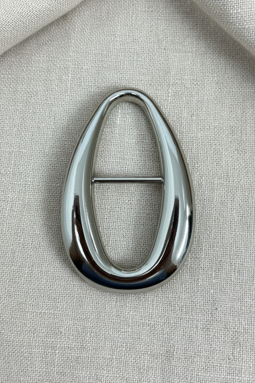 Passante oval gota prata cromado sobre fundo de tecido linho