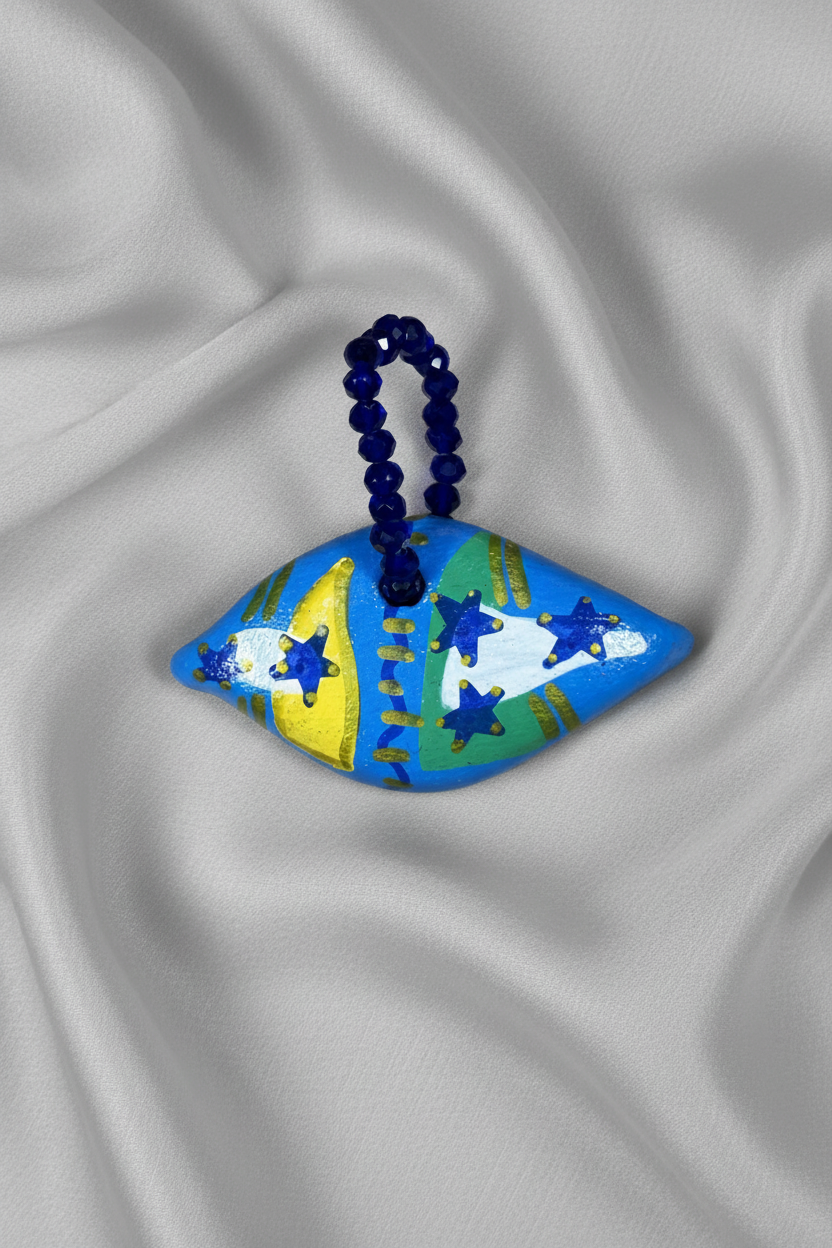 Pingente azul losango com faixa verde diagonal em close sobre tecido fluido