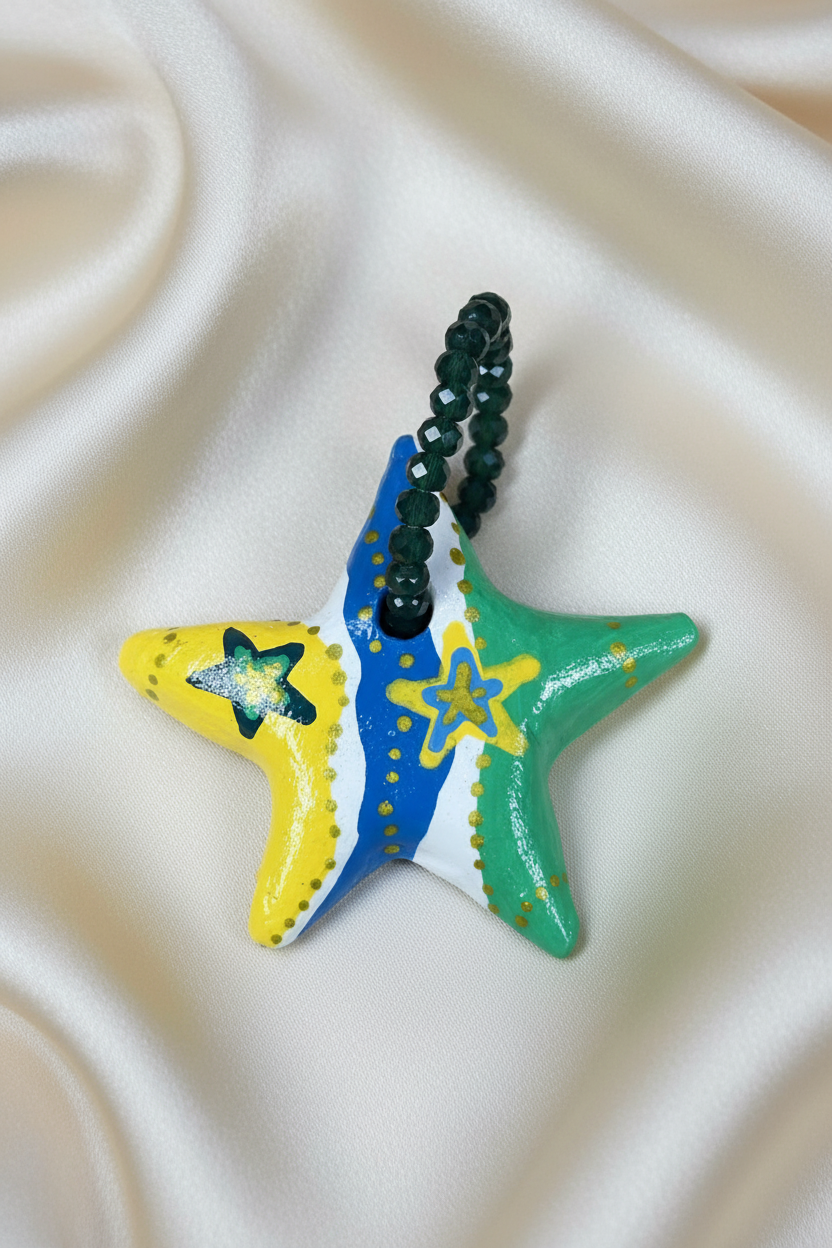 Pingente em formato de estrela com cores da bandeira em close sobre tecido fluido