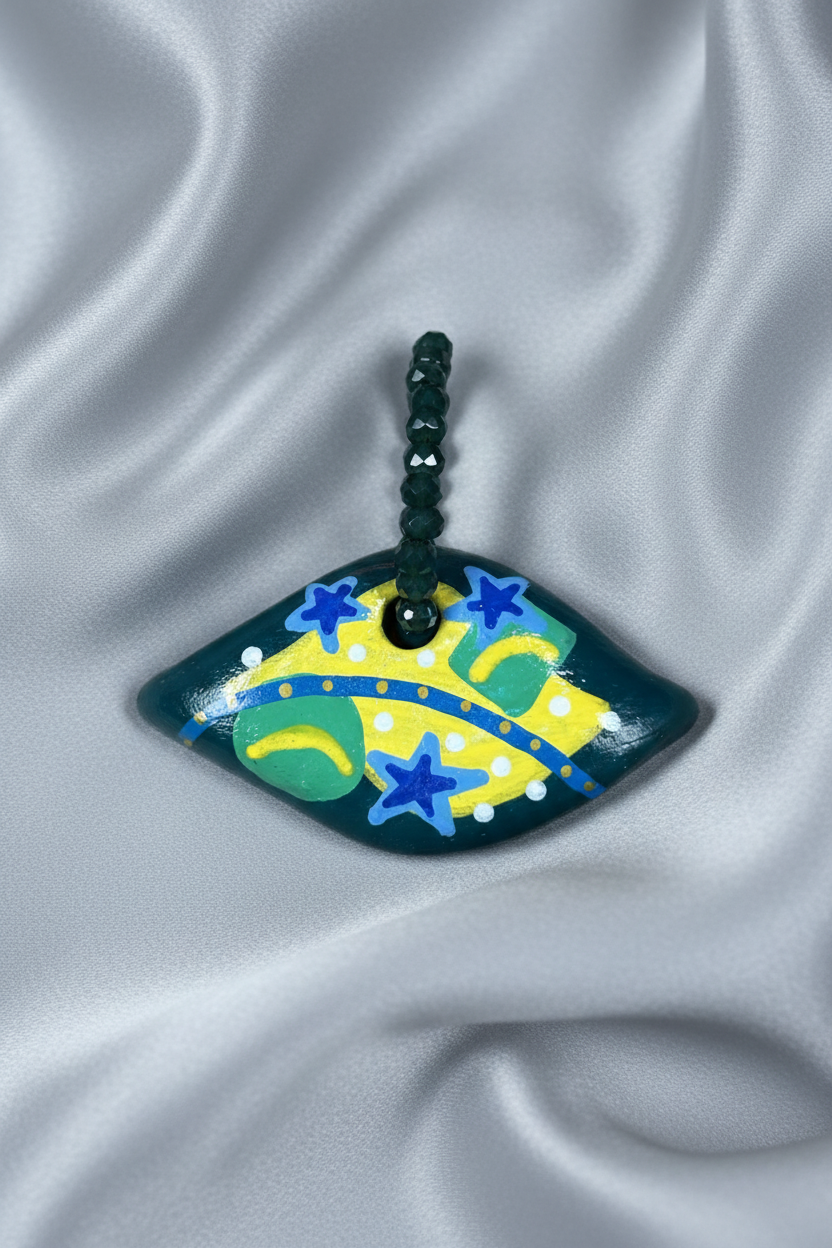 Pingente losango escuro com bandeira do Brasil em close sobre tecido fluido