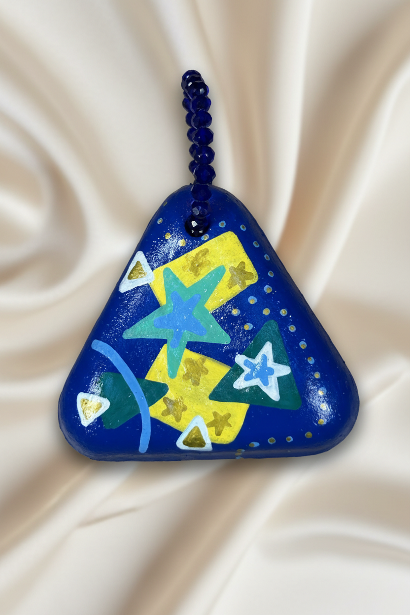 Pingente triangular azul com estrela turquesa em close sobre tecido fluido